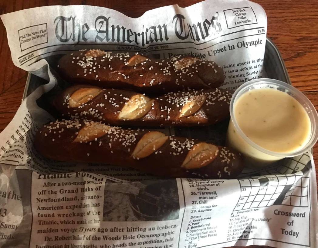 A tray with pretzels and mustard on it.