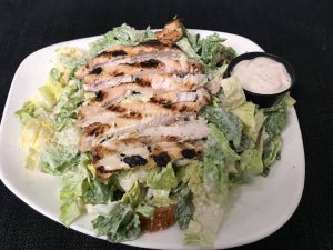 A chicken salad with dressing on a white plate.