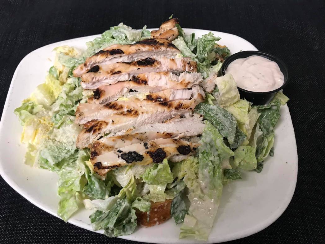 A chicken salad with dressing on a white plate.