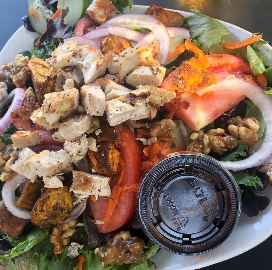 A salad with chicken and vegetables on a plate.