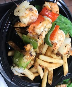 Shrimp skewers and french fries on a plate.