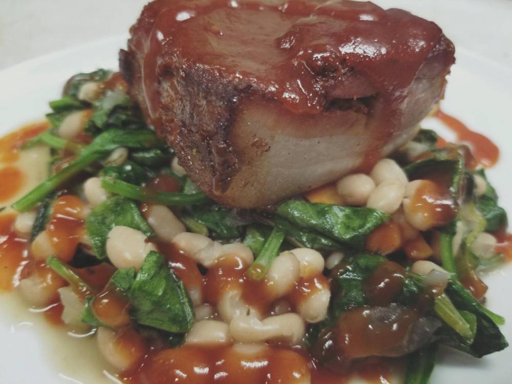 A plate with pork and beans on it.