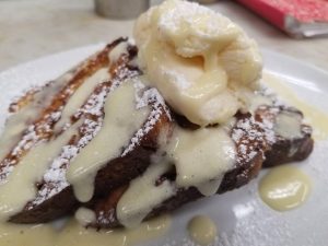 A plate of french toast with ice cream and syrup.