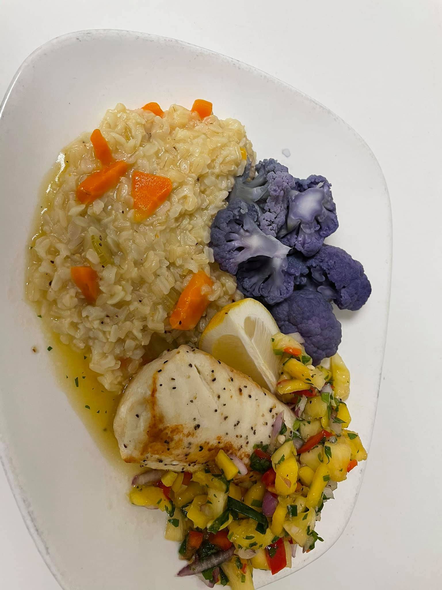 A plate with fish, vegetables and rice.