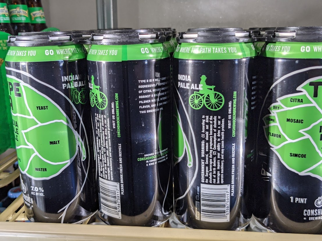 Four cans of green beer sitting on a shelf.