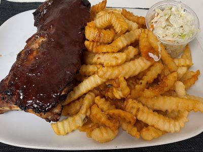 A plate with ribs, fries and coleslaw.